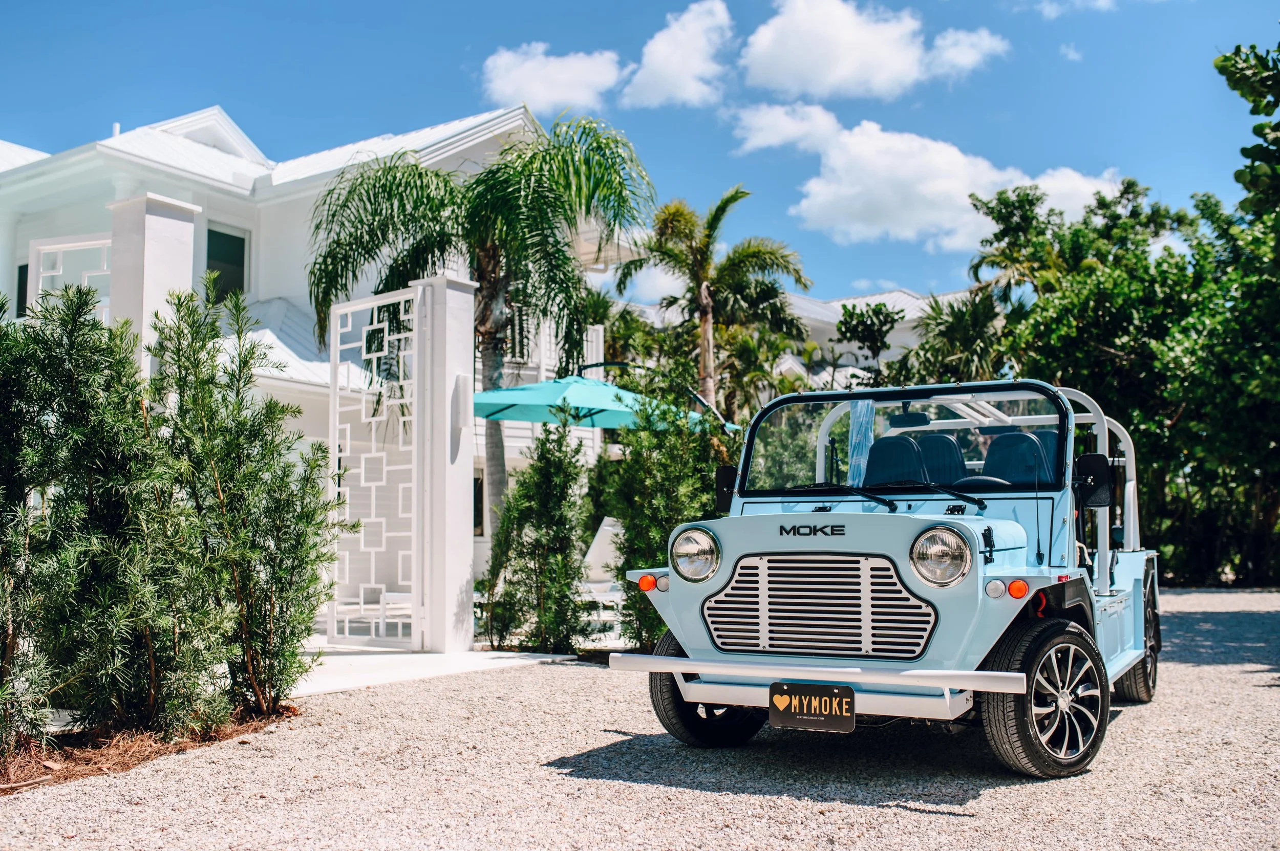 Classic white Moke parked on a sunny tropical beach with palm trees
